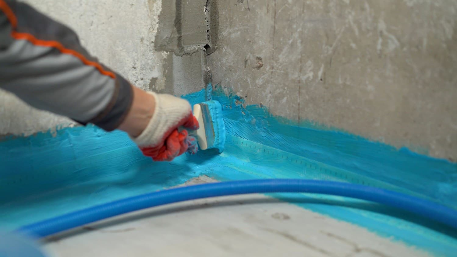 Handwerker trägt mineralische Dichtungsschlämme auf eine Kellerinnenwand in Duisburg auf