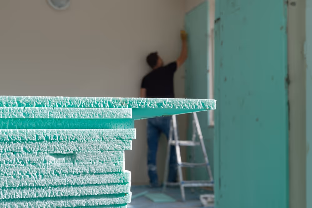 Handwerker montiert eine kapillaraktive Dämmplatte zur Innendämmung an einer Wohnraumwand in Duisburg